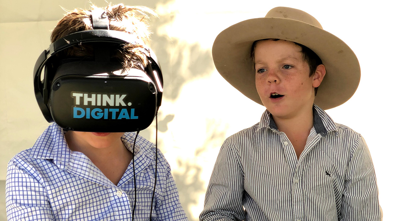 Two boys; one is wearing a "Think Digital" VR headset.