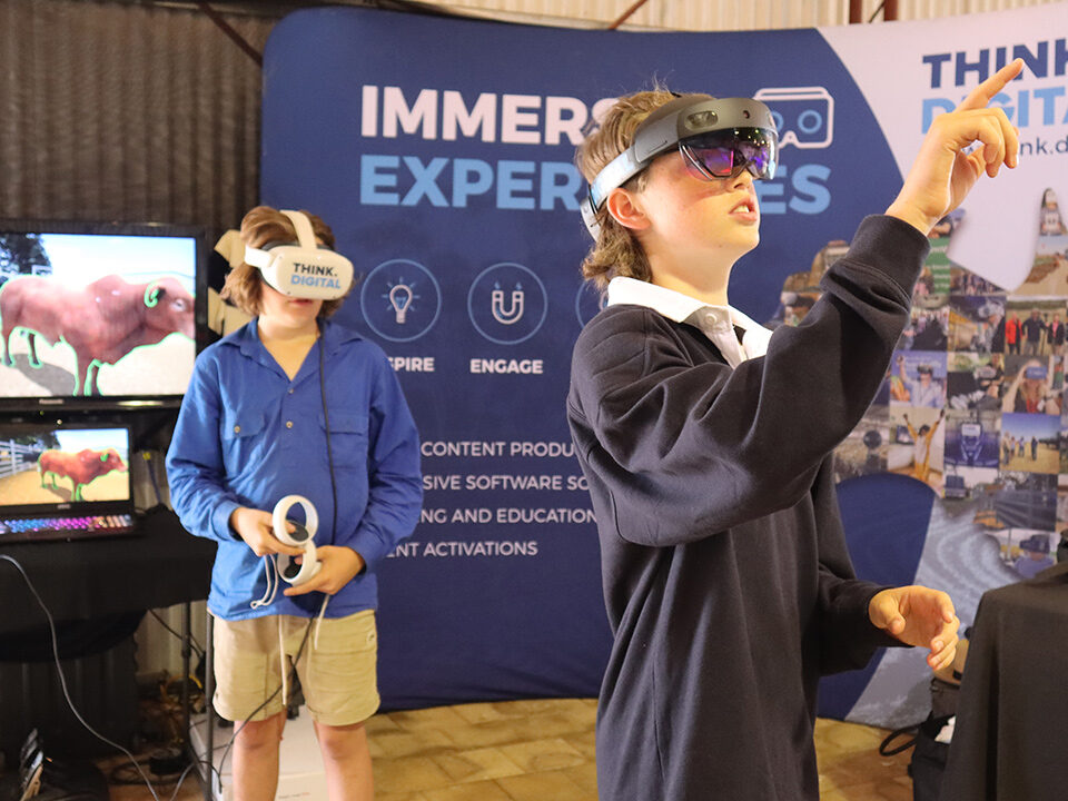 A boy wearing an AR headset in the foreground and a boy wearing a VR headset in the background.